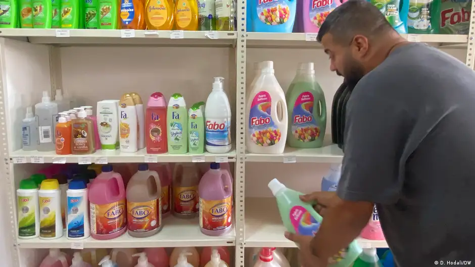 A man takes a bottle of washing detergent from a shelf in cooperative supermarket Mann wa Salwa in Beirut, Lebanon