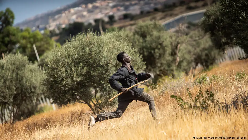 صورة من: Ja vier Bernardo/AP/dpa/picture alliance - مهاجر يجري عبر حقل في جيب مليلية الإسباني.A migrant runs across a field in the Spanish enclave of Melilla