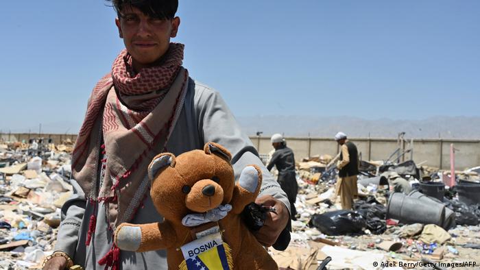 Ein Mann mit einem Stoffteddy auf dem Schrottplatz von Bagram