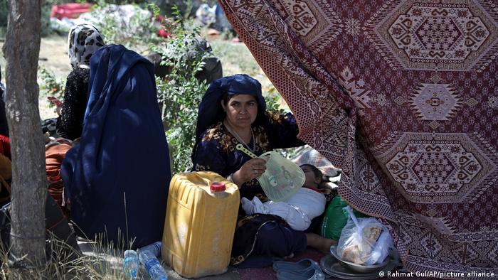 A woman fans a sleeping child in a Kabul park (photo: Rahmat Gul/AP/picture-alliance)