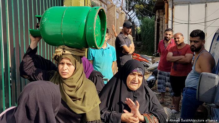 A Lebanese woman carries a gas canister on her head.