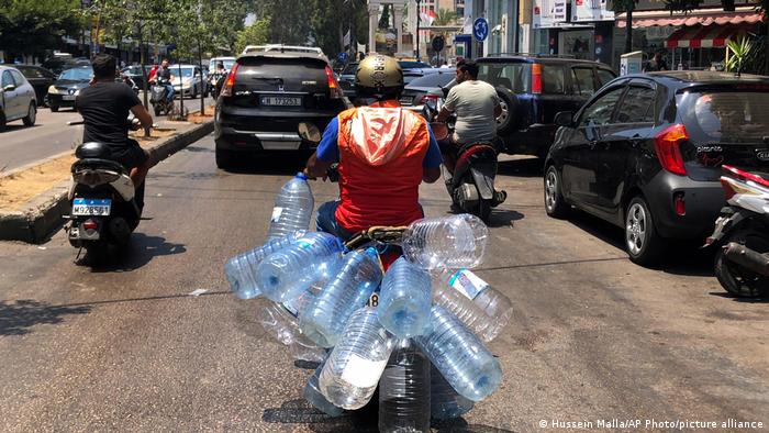 Mofa-Fahrer transportiert leere Wasserflaschen aus Plastik in Beirut.