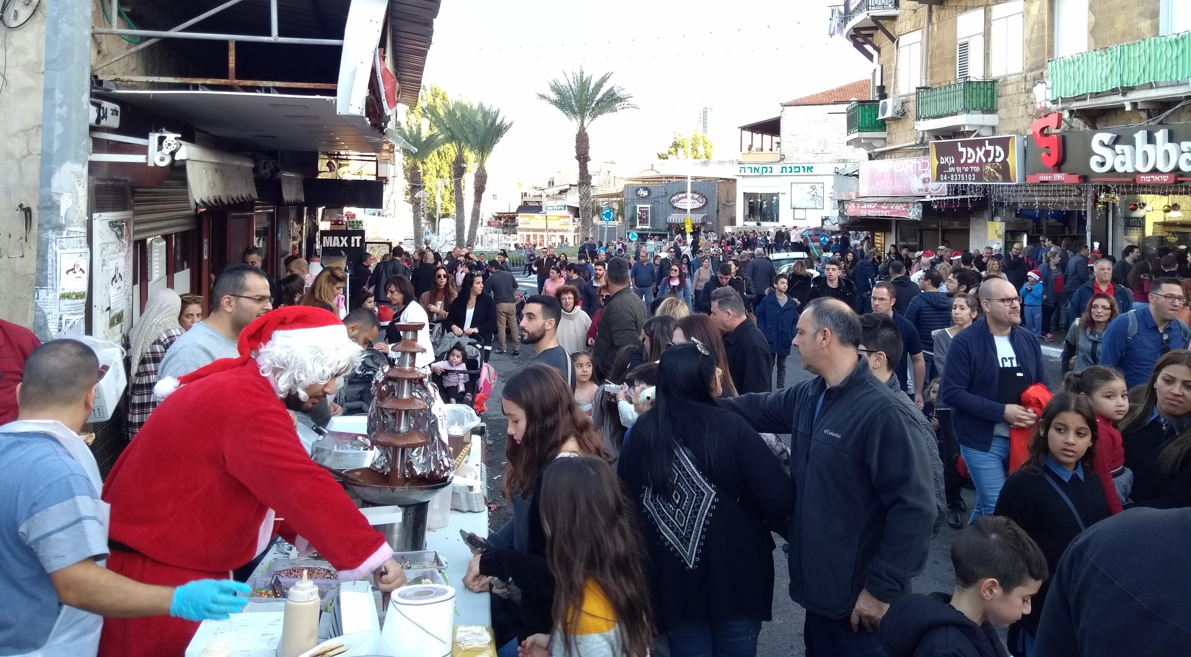 رواد مهرجان عيد الأعياد في حيفا يمشون في شارع مزدحم. Festivalgoers walk along a crowded street at Haifa's Holiday of Holidays (photo: Noam Yatsiv)