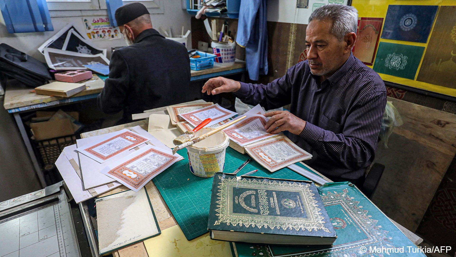 A man assembles pages together to be glued into a volume at a workshop for restoring copies of the Holy Koran, Islam's holy book -- an increasingly popular practice as the price of new Korans goes up in Libya