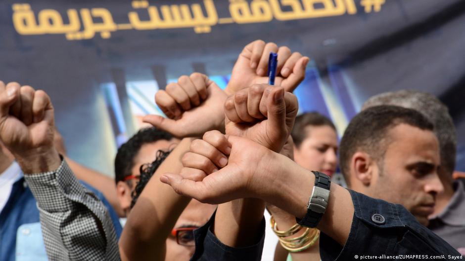 Journalists protest against curbs to freedom of speech in front of a placard in Arabic which reads "Journalism is not a crime!" (photo: 