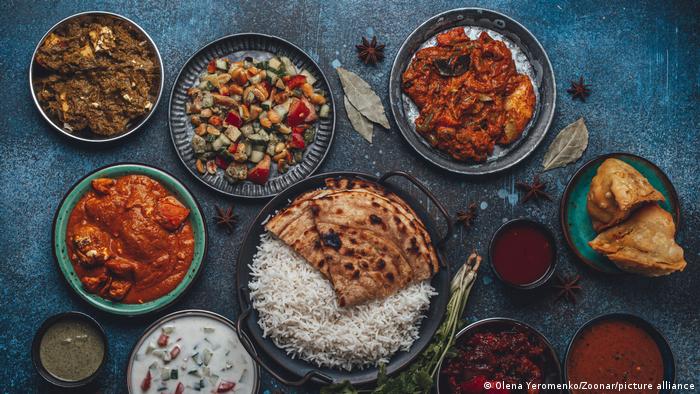 Various Indian specialities on a platter decorated with spices; among them rice and chapati and various sauces, curries and vegetables