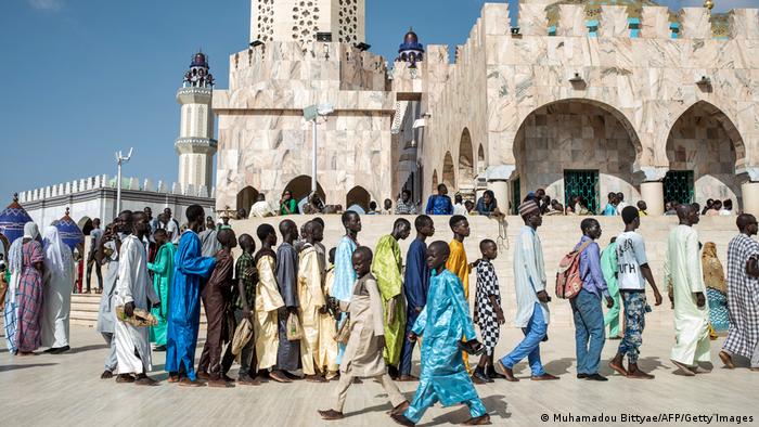 Brightly dressed pilgrims stand in line outside the Grand Mosque