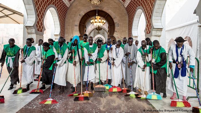 Mitglieder der Muriden-Bruderschaft fegen gemeinsam den Boden der Moschee.