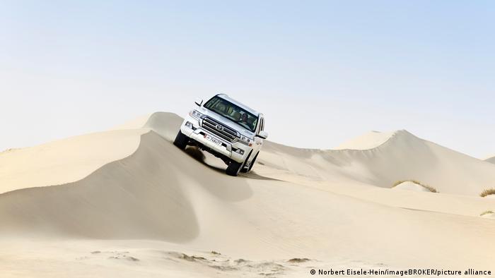 A jeep driving over sand dunes