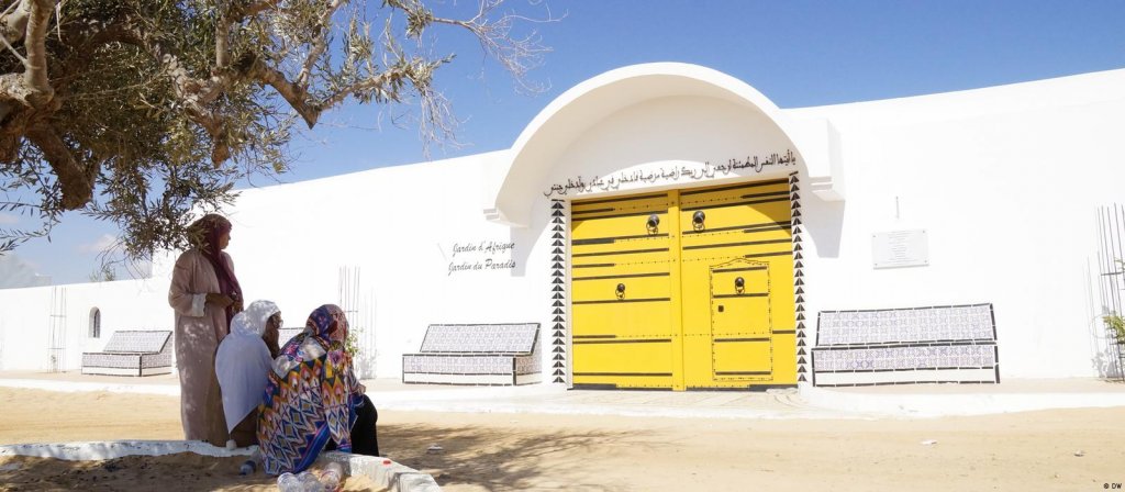 Women stand and sit in the shade of a tree outside the cemetery known as the "Garden of Africa" (photo: DW)