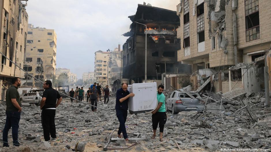 Palestinians salvage household items from damaged apartments following Israeli airstrikes