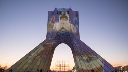 The portrait of a nurse in a protective suit is projected onto the Azadi monument in Tehran.