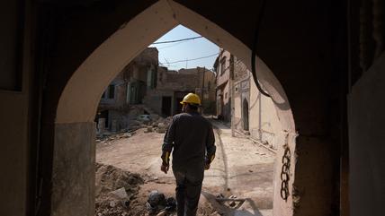 A picture shows an Iraqi architect exiting a traditional house amid renovations in the old town of Iraq‘s northern city of Mosul.