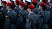 Several rows of German army recruits wearing ceremonial service uniforms stand in formation with their backs to the camera, November 2023