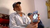 Displaced Syrian man Walid Muhammad Abdel-Baqi shows pictures of his dead son Walid on his phone