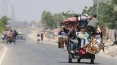 Junge Menschen in Gaza sitzen auf einem mit Möbeln und anderen Habseligkeit bepacktem Karren und verlassen die zerstörte Stadt