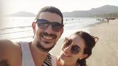 Selfie of a couple at the beach. They wear sunglasses.