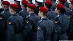 Several rows of German army recruits wearing ceremonial service uniforms stand in formation with their backs to the camera, November 2023