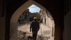 A picture shows an Iraqi architect exiting a traditional house amid renovations in the old town of Iraq‘s northern city of Mosul.