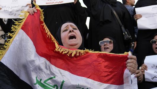 Irakische Frauen demonstrieren, darunter eine Frau, die die irakische Flagge hält (Foto: Picture Alliance/AP | H. Mizban)